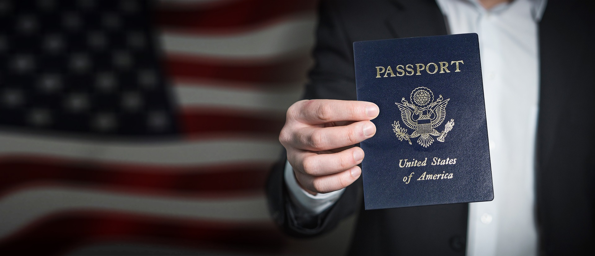 Frau hält Reisepass vor US-amerikanischer Flagge in Kamera